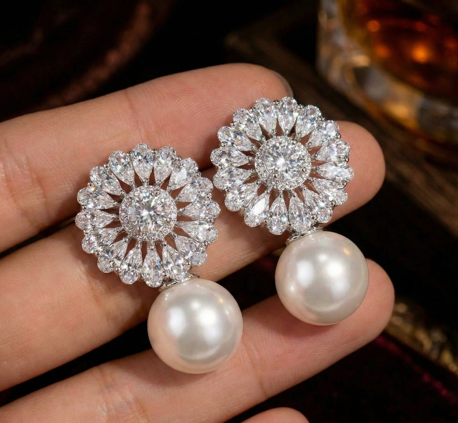 pearl earrings held in a hand with a blurred background
